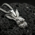 Load image into Gallery viewer, Polished silver rabbit necklace pendant on black volcanic stone background, crisp sculpted hare face detail, high-end product shot

