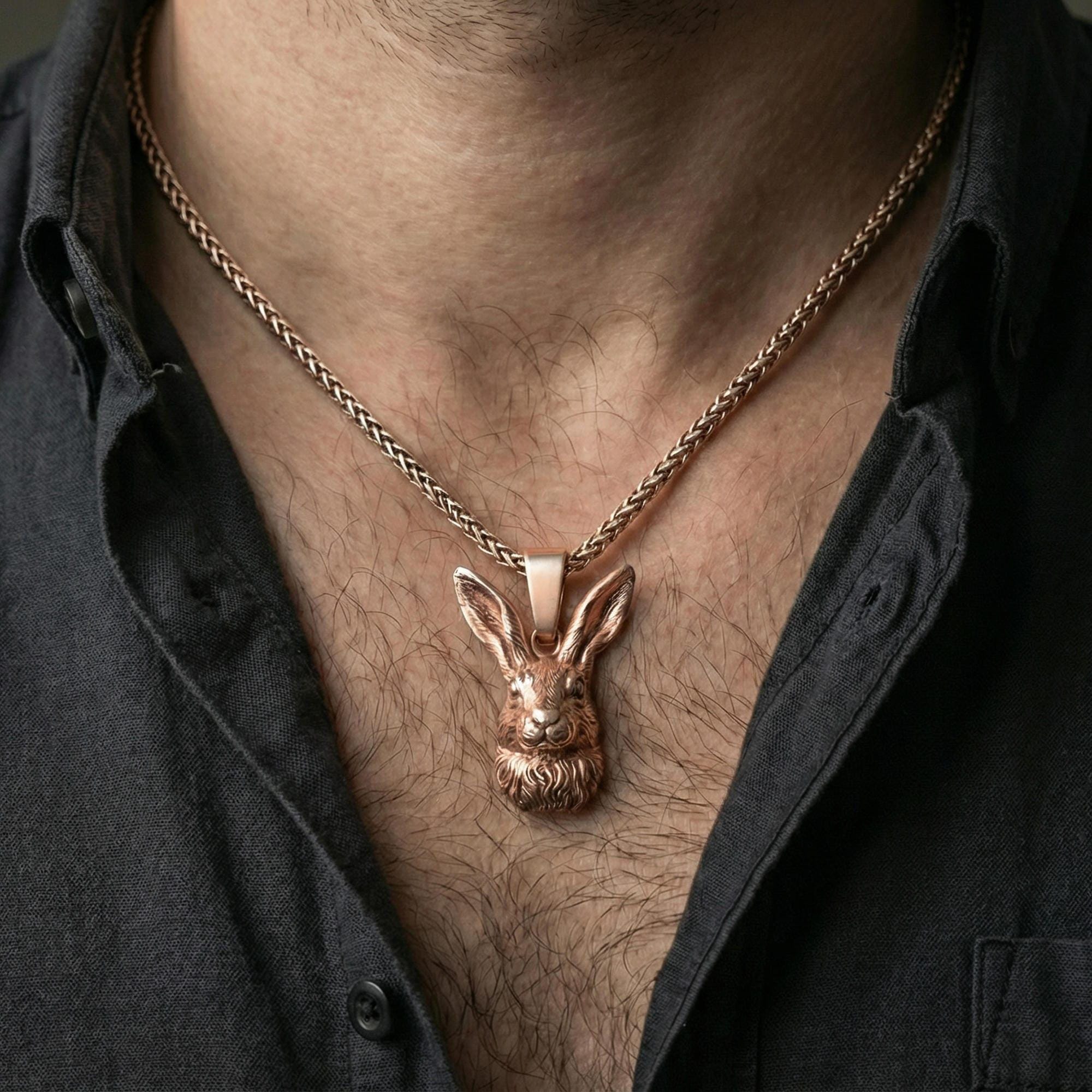 Rose gold plated rabbit pendant necklace worn on neck, lifestyle composition with dark clothing, crisp rabbit silhouette