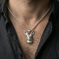 Load image into Gallery viewer, Polished silver rabbit pendant on chain worn on neck, natural lifestyle framing, rabbit face and ears clearly visible
