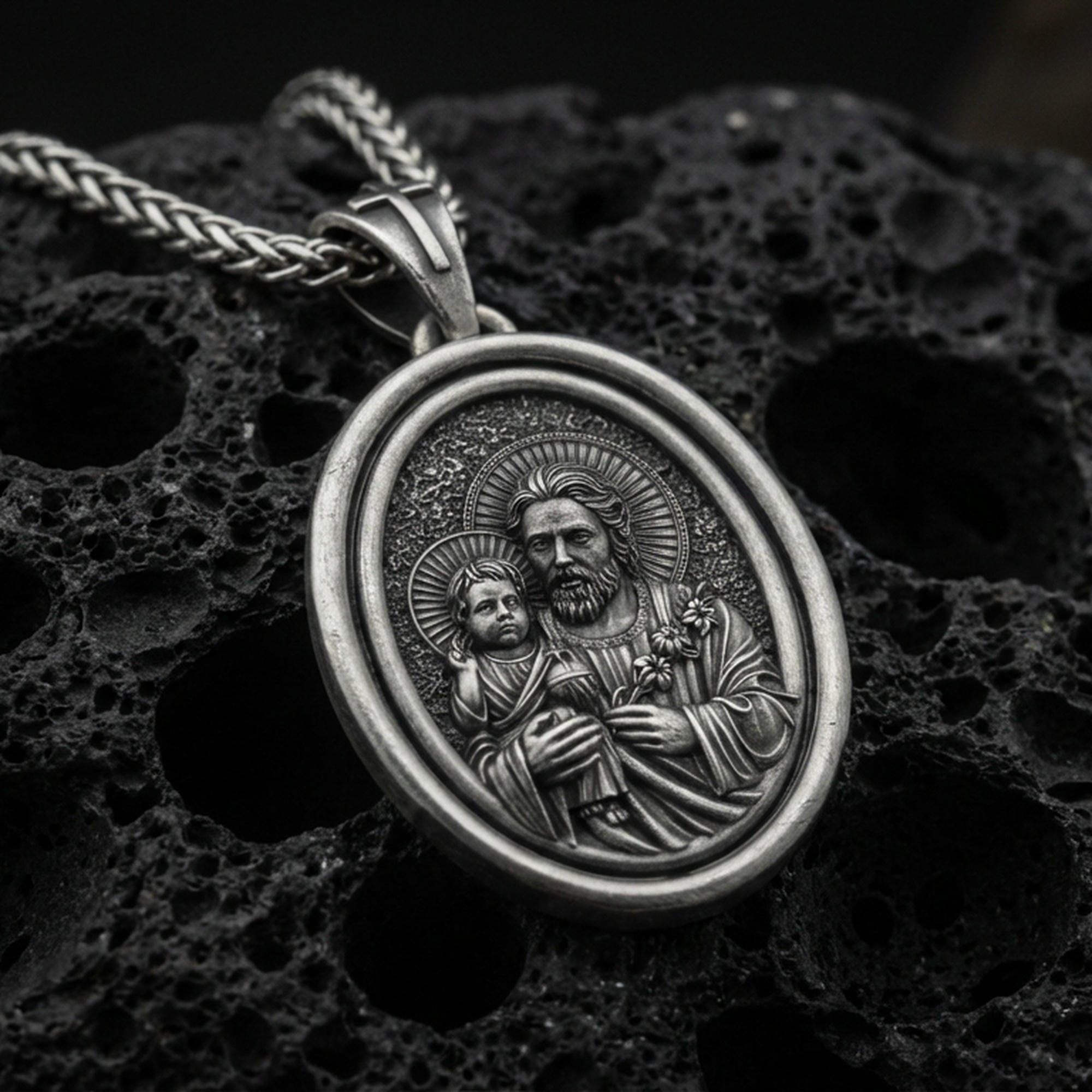 Oxidized Saint Joseph rotating pendant on textured volcanic rock, macro close-up, Catholic medallion with halo detail, premium studio lighting