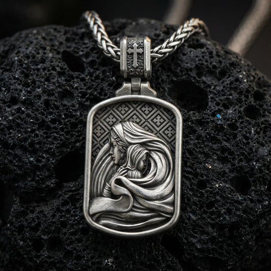 Oxidized Virgin Mary and Baby Jesus pendant on textured volcanic rock, macro close-up, Christian relief detail, premium studio lighting