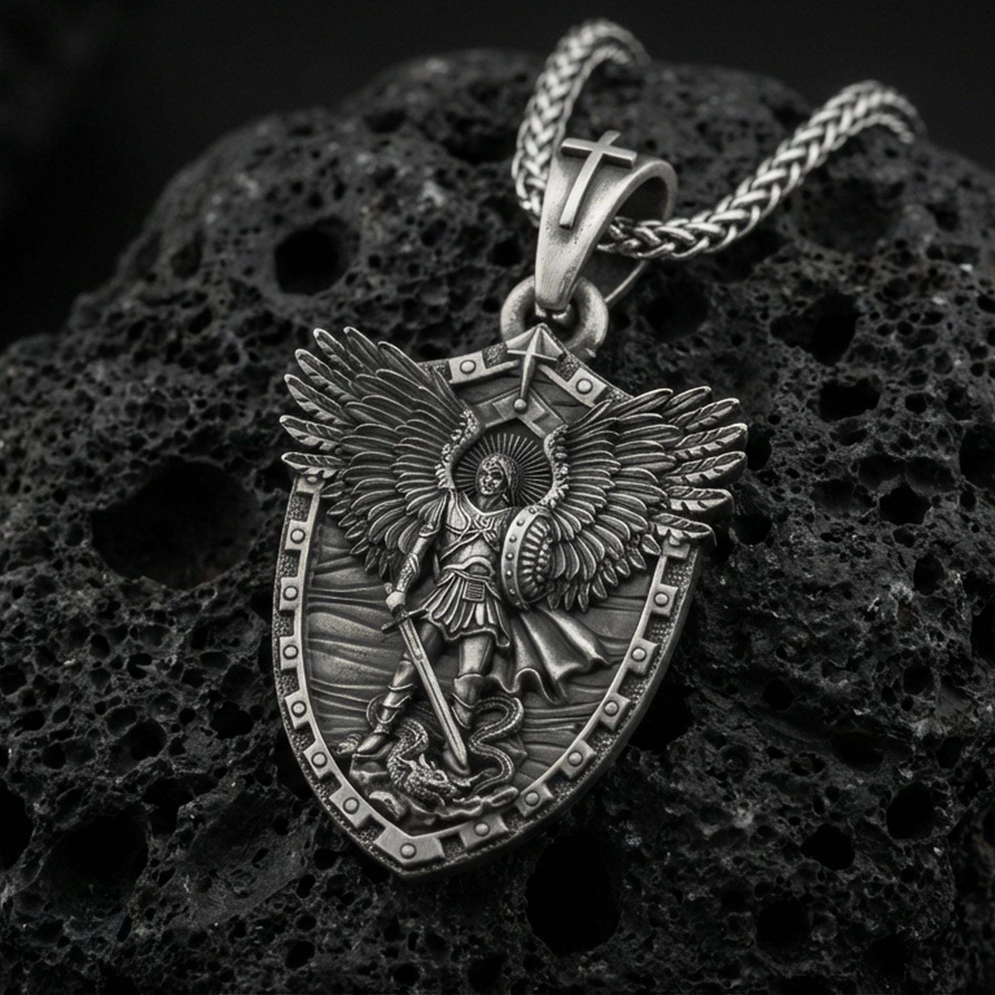 Oxidized Archangel Michael shield pendant on textured volcanic rock, macro close-up, detailed wings and sword relief, premium studio lighting
