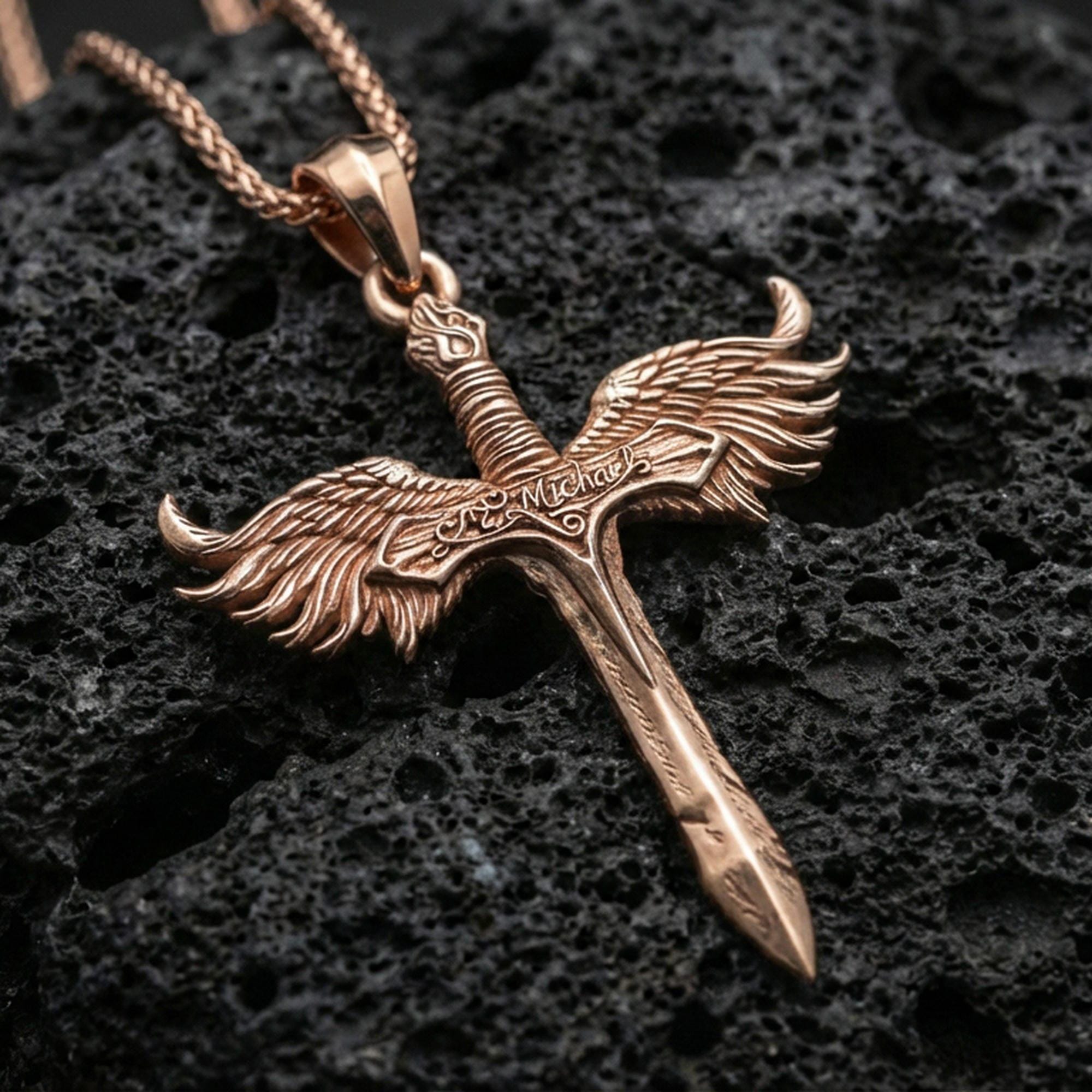 Rose gold plated Archangel Michael winged sword pendant on volcanic rock, premium macro product photo, sharp blade profile and feather texture