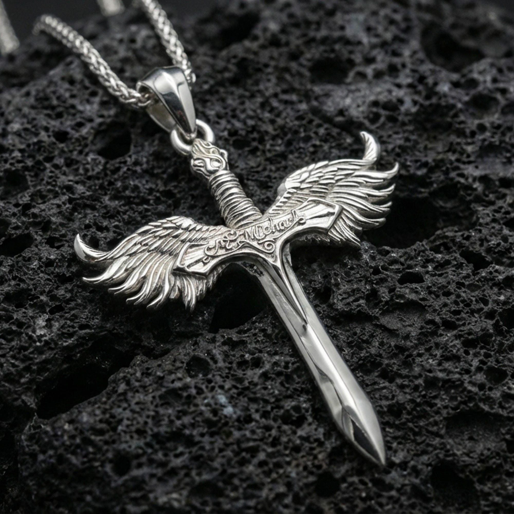 Polished silver Archangel Michael sword necklace pendant on black volcanic stone background, crisp feather wings and blade edge, high-end product shot