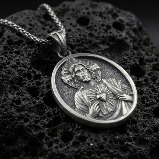 Oxidized Sacred Heart of Jesus pendant on textured volcanic rock, macro close-up, Jesus medal relief detail, premium studio lighting