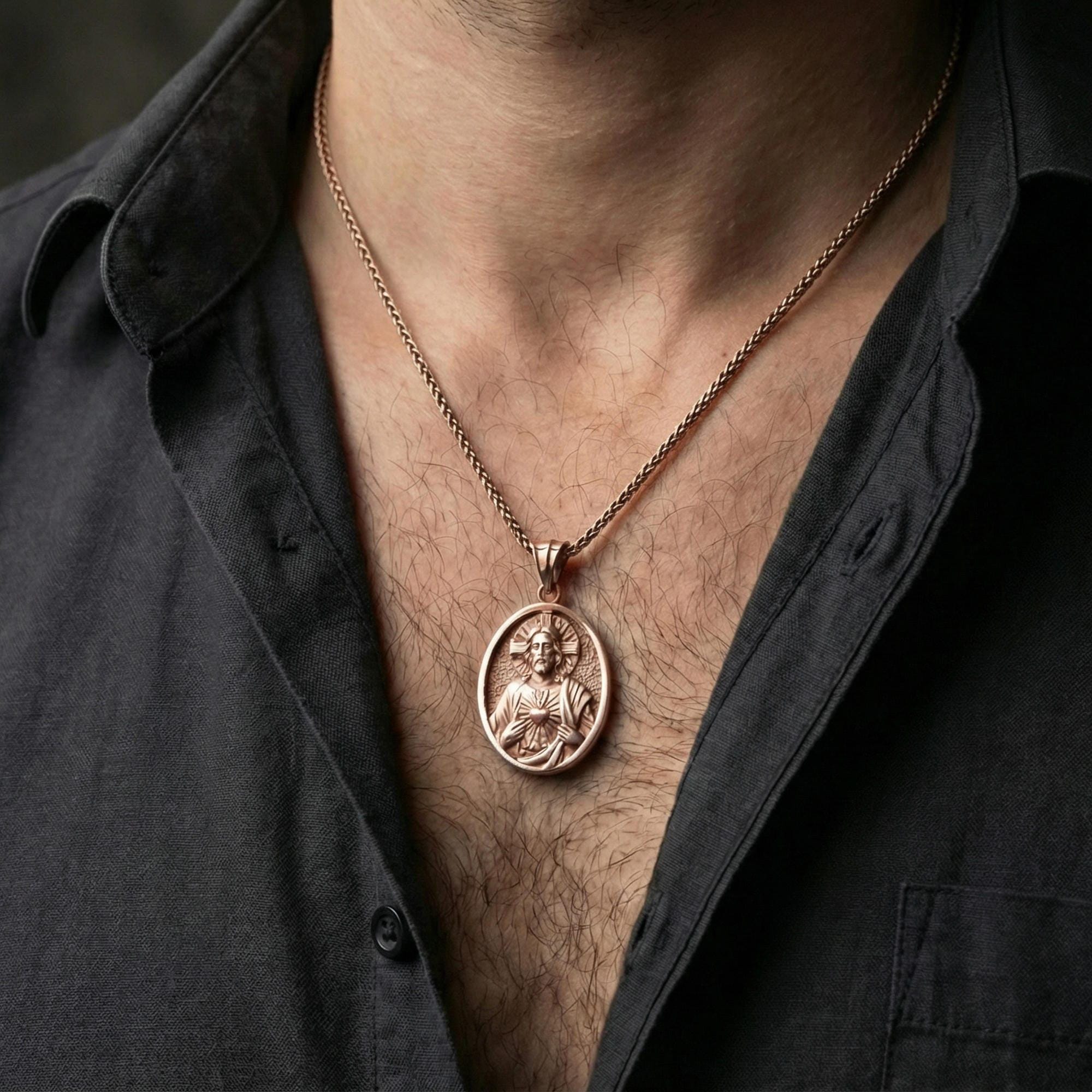 Rose gold plated Sacred Heart Jesus pendant necklace worn on neck, lifestyle composition with dark clothing, crisp round medallion silhouette