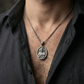 Load image into Gallery viewer, Oxidized Sacred Heart of Jesus pendant necklace worn on neck, lifestyle close-up on dark outfit, round medal centered
