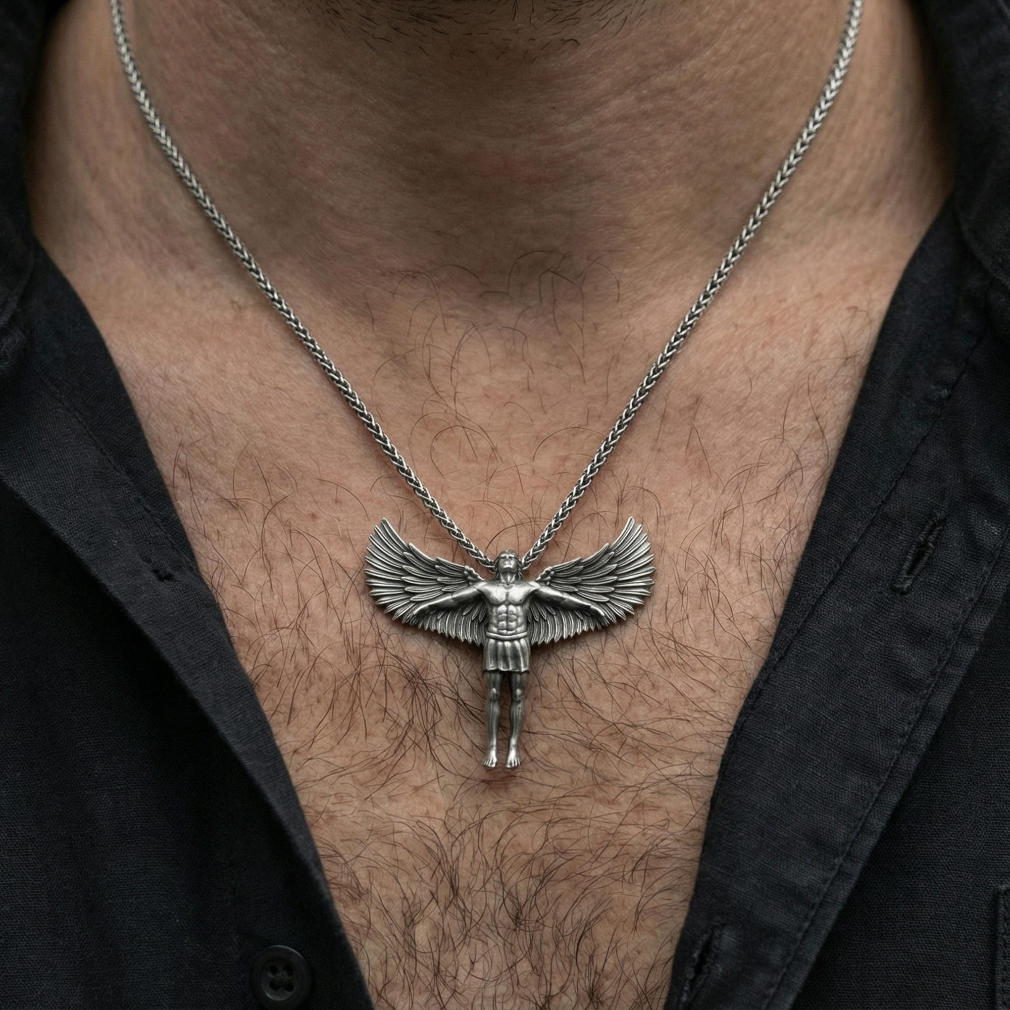 Oxidized Archangel Michael pendant necklace worn on neck, lifestyle close-up on dark outfit, angel figure centered with wings visible