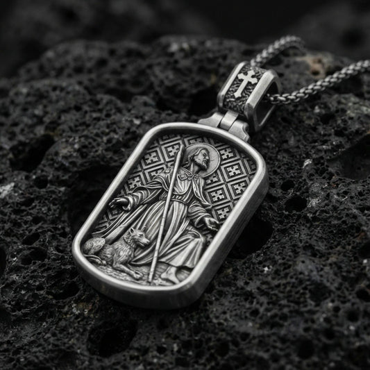 Oxidized Saint Roch dog tag pendant on textured volcanic rock, macro close-up, saint with staff and dog relief, premium studio lighting