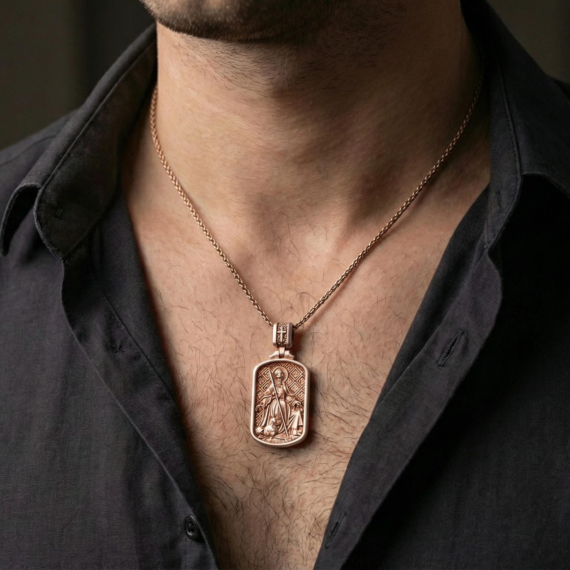 Rose gold plated Saint Andrew dogtag pendant necklace worn on neck, dark clothing lifestyle composition, rectangular pendant silhouette in focus