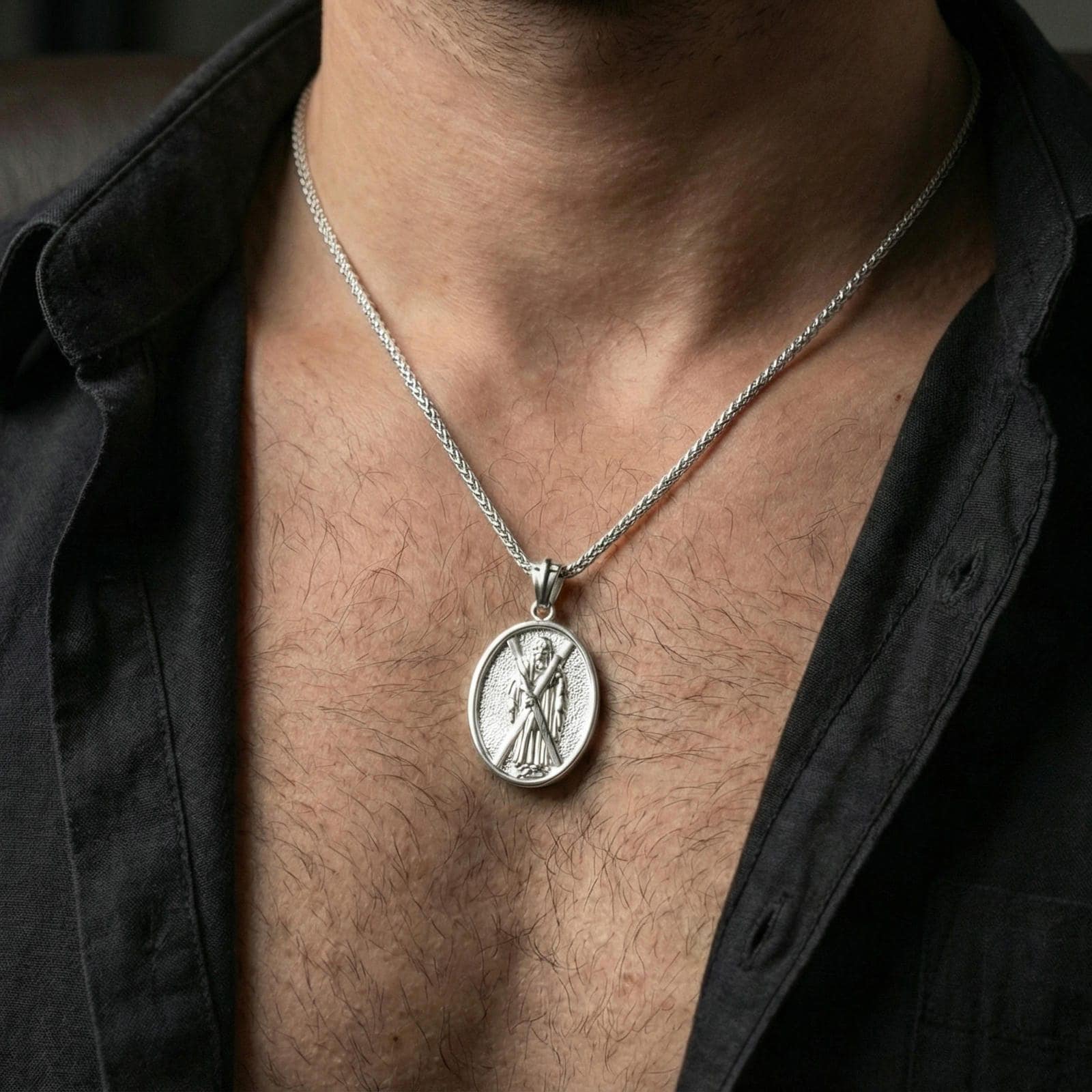 Polished silver Saint Andrew oval medallion pendant worn on chain, lifestyle framing, apostle figure and cross engraving visible