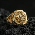 Load image into Gallery viewer, Gold plated lion signet ring on volcanic rock, octagon crest design with sculpted lion profile and dark recessed texture for strong contrast, macro lighting

