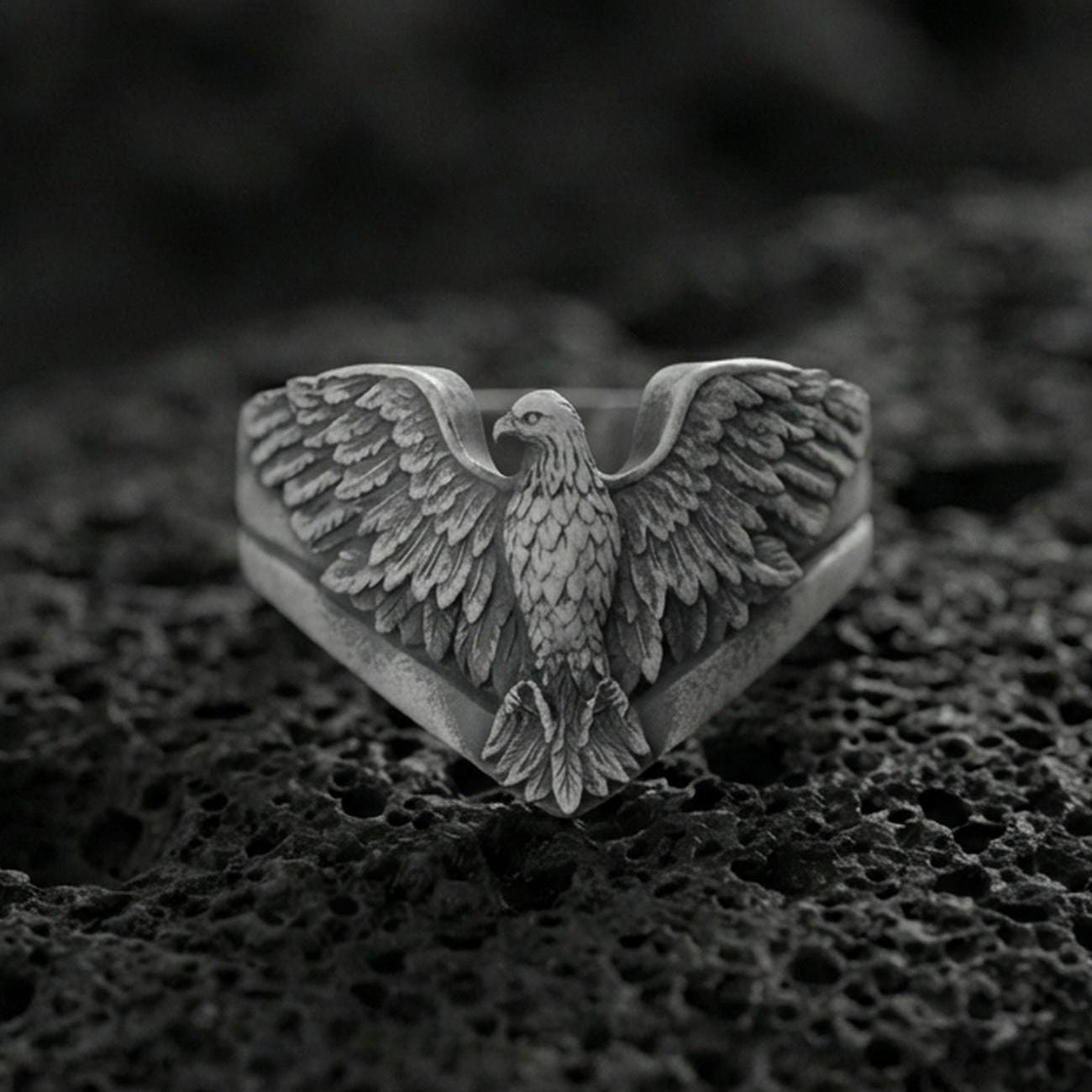 925 sterling silver eagle ring on volcanic stone, oxidized finish highlighting the layered feather engraving and spread wings