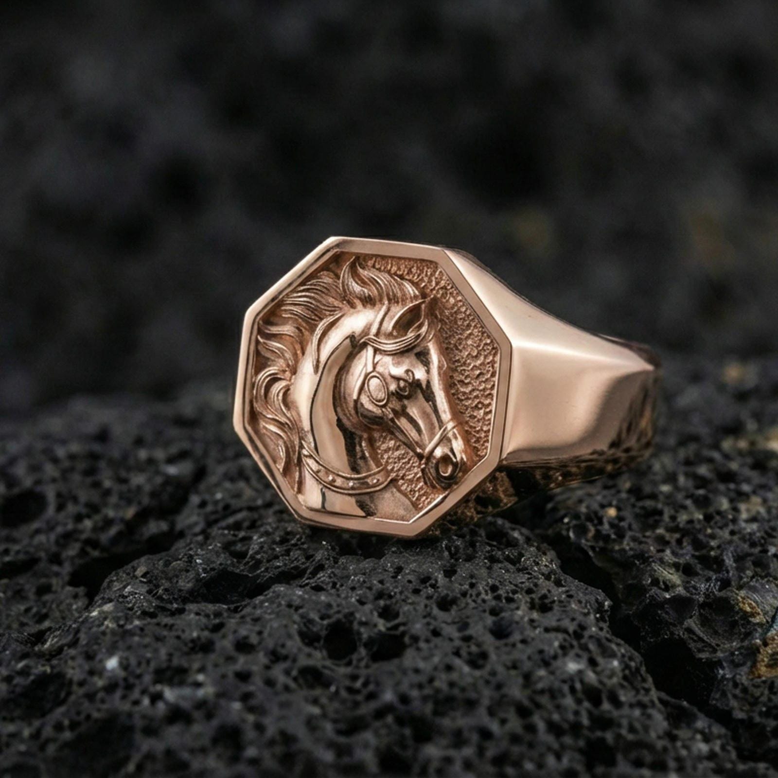 Rose gold plated horse signet ring on volcanic rock, crisp macro photo showcasing the octagonal top and detailed horse head relief