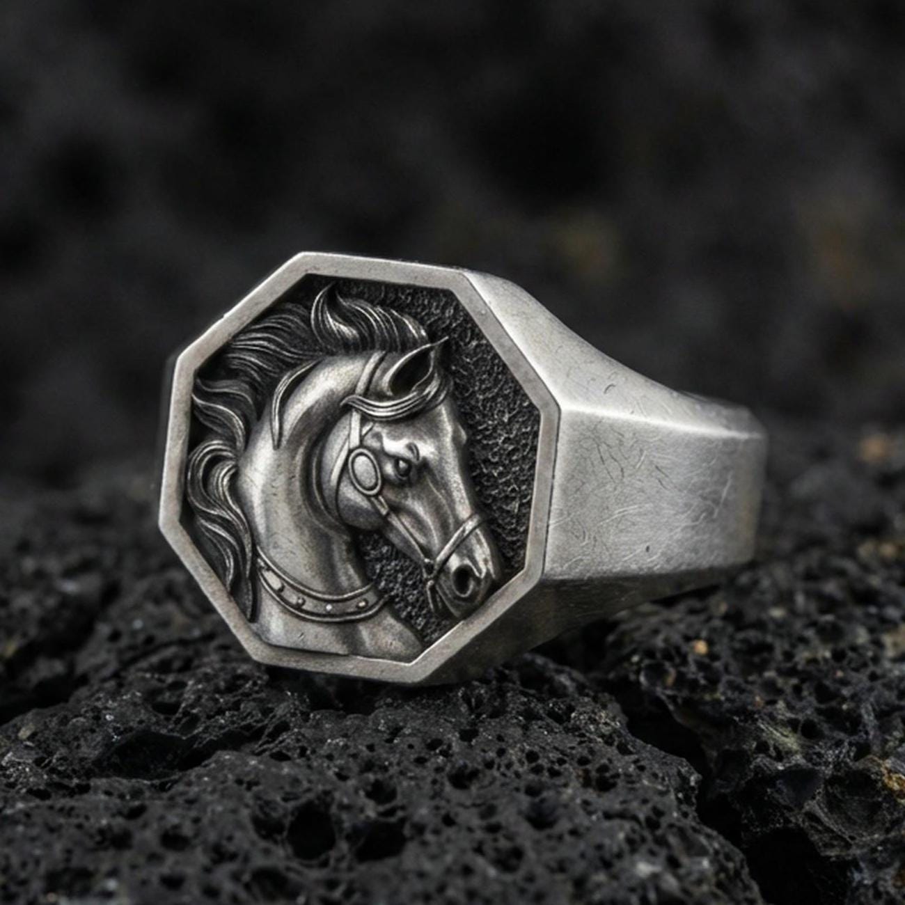 Oxidized sterling silver horse signet ring on textured volcanic rock, octagon face with detailed stallion portrait in macro studio shot
