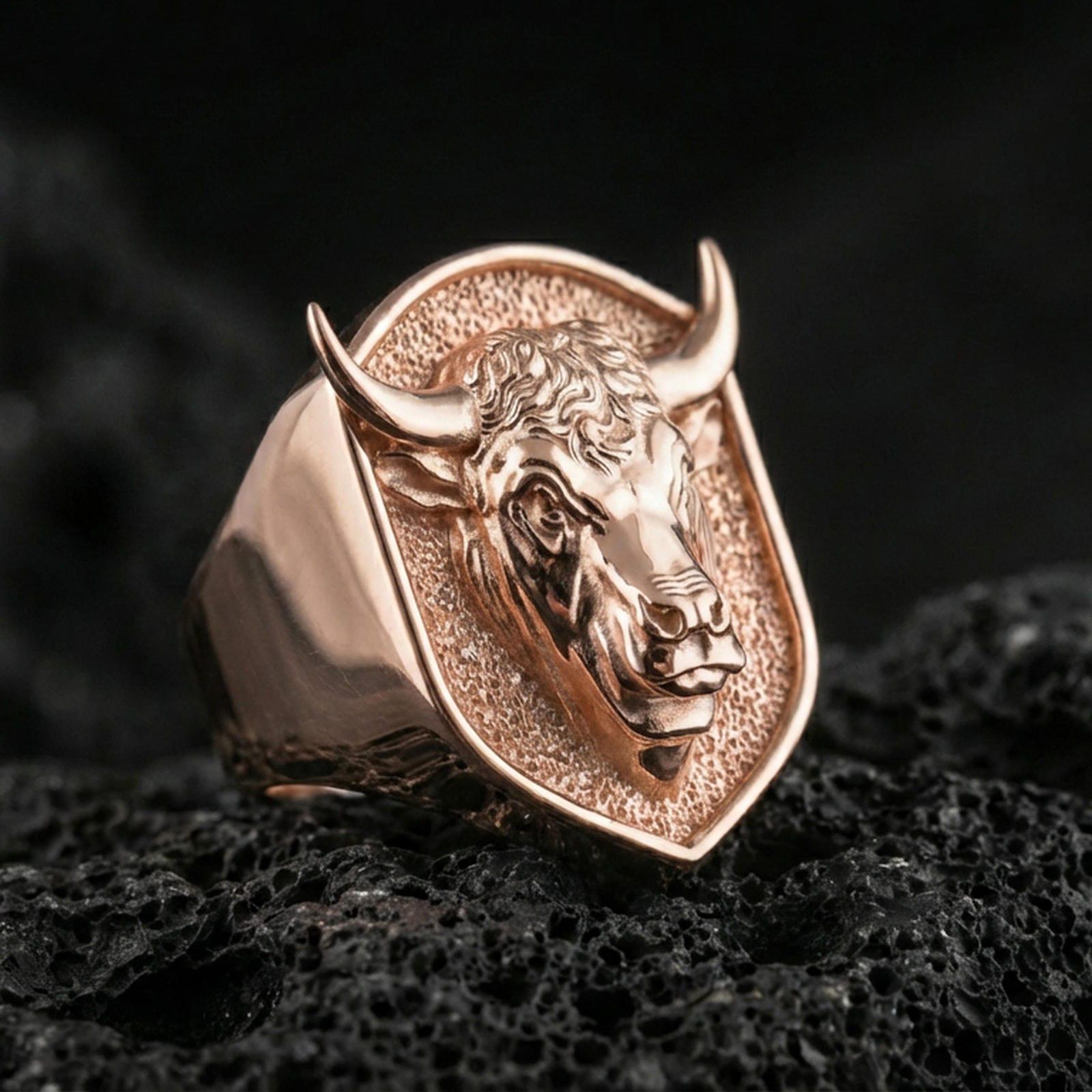 Rose gold plated bull signet ring on volcanic rock, sharp macro product photo showcasing the shield top and bold bull relief