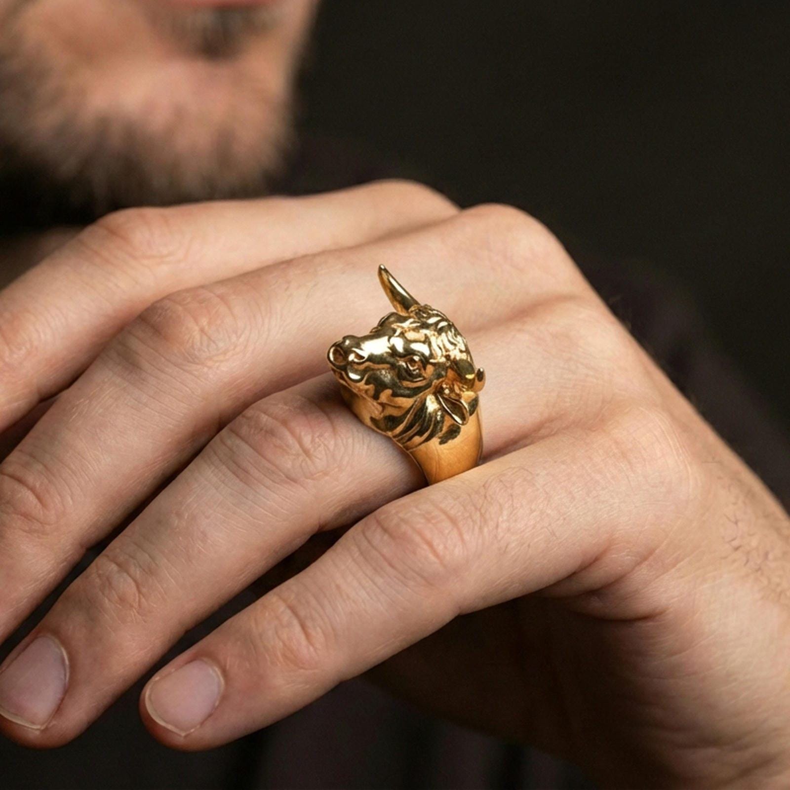 Gold plated bull head ring worn on finger, lifestyle wear shot emphasizing the horned design and strong masculine presence