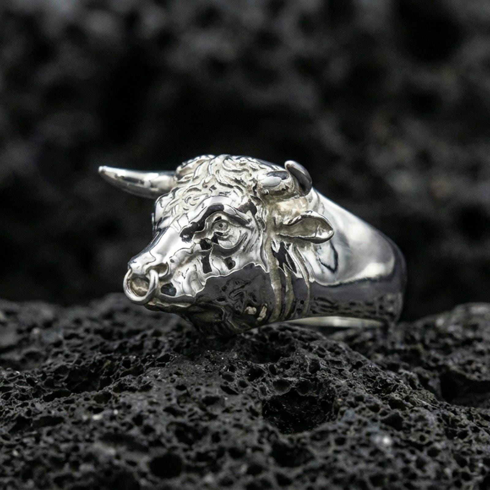 Polished silver bull ring on volcanic rock surface, close-up highlighting realistic facial sculpting and smooth band profile