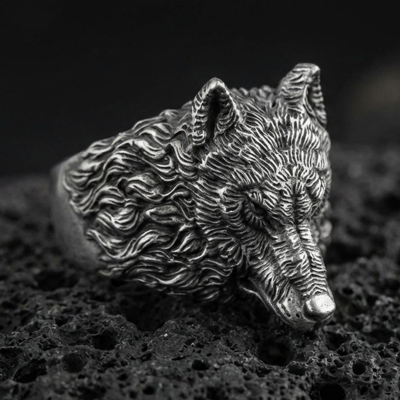Oxidized sterling silver wolf head ring on volcanic rock, detailed fur texture macro closeup
