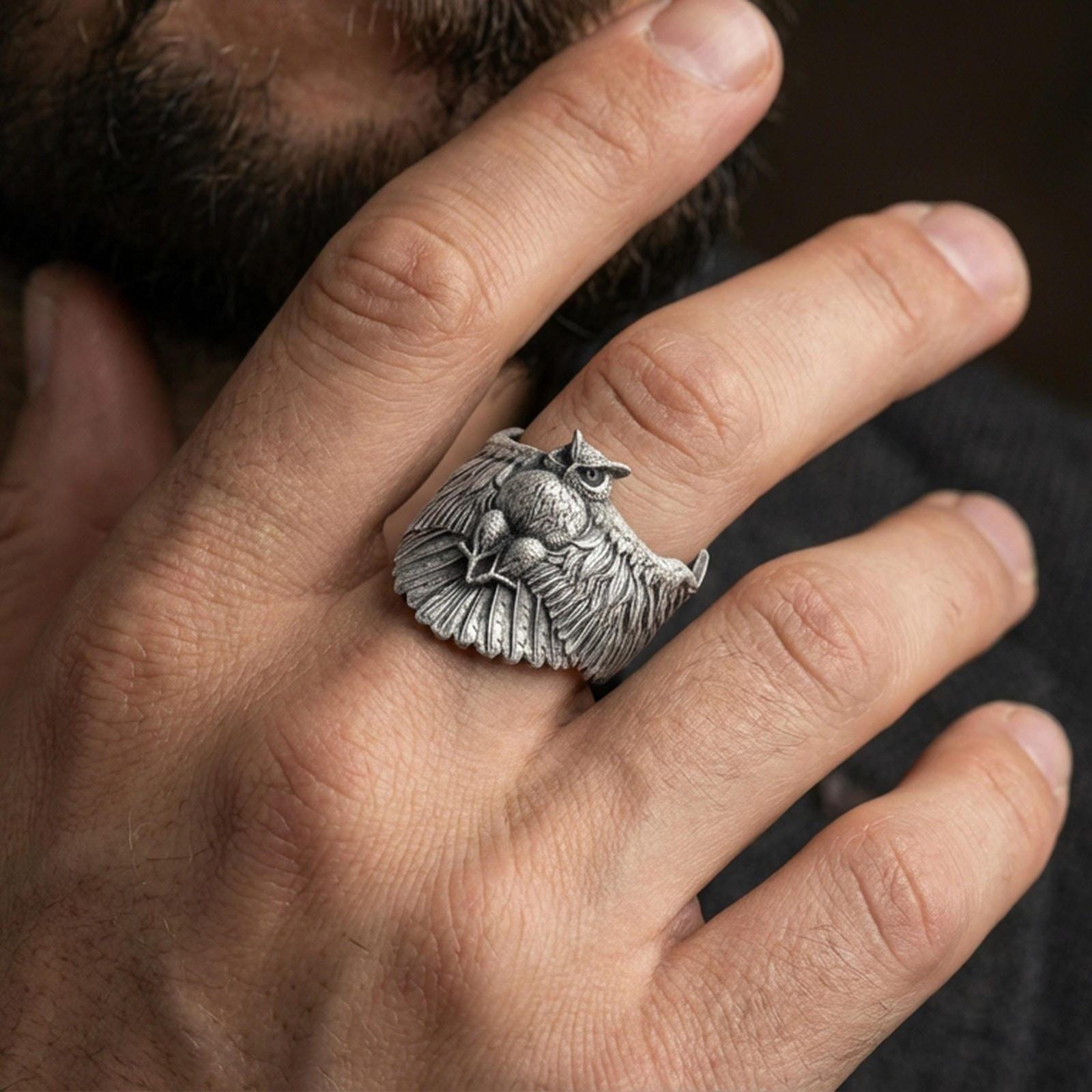 Oxidized owl ring worn on finger, lifestyle close-up focusing on the outstretched wings and detailed feather engraving