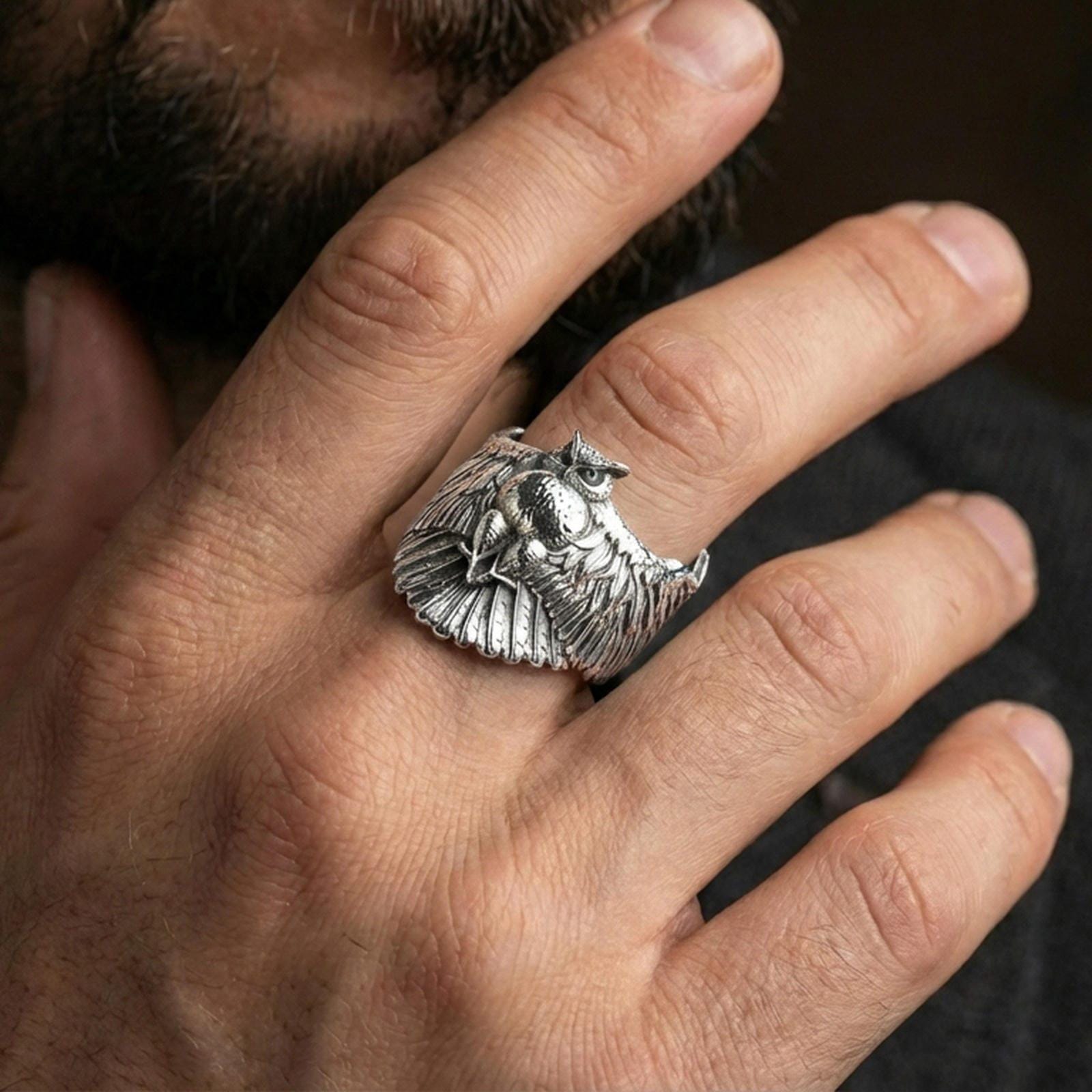 Polished silver owl ring on finger, natural hand pose highlighting the wide wing design and textured owl body relief