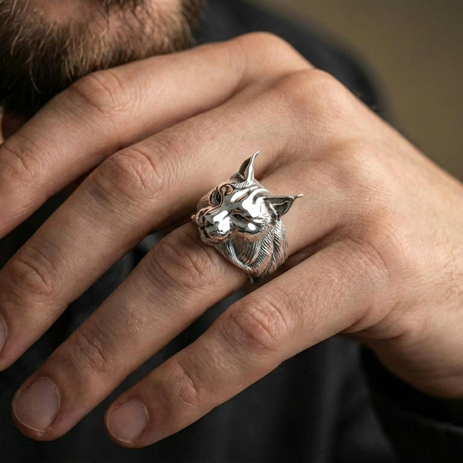 Polished silver lynx head ring on finger, natural hand pose highlighting the pointed ears, whisker pad detail, and bold animal silhouette