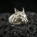 Load image into Gallery viewer, Polished silver lynx head ring on volcanic rock surface, close-up highlighting the sculpted whisker pads, sharp ear tips, and clean metal contours
