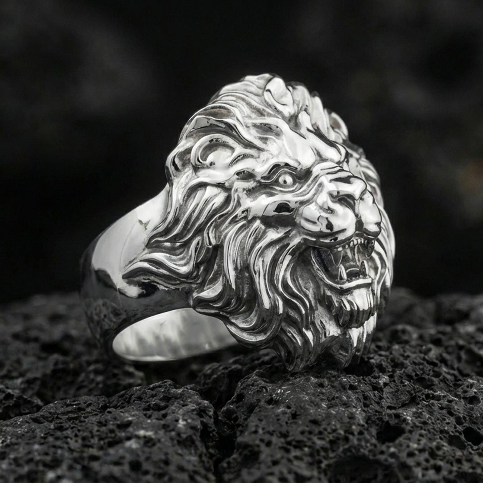 Polished silver lion head ring on volcanic stone, sharp mane carving and bold sculpted face