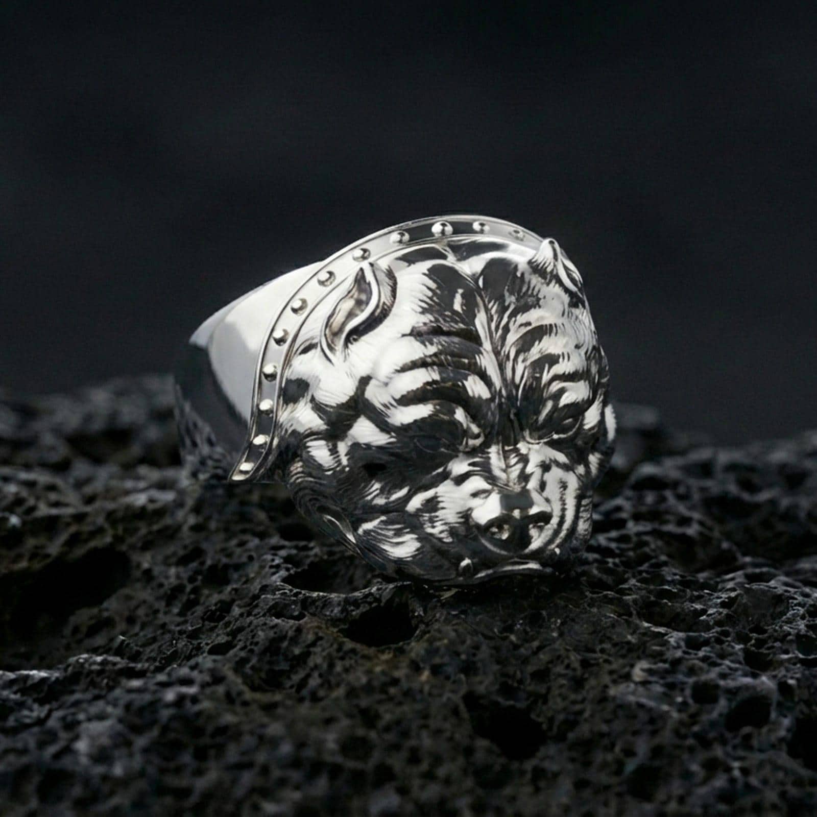 Polished silver bulldog ring on volcanic rock surface, close-up highlighting the sculpted dog face, strong jawline, and clean band profile