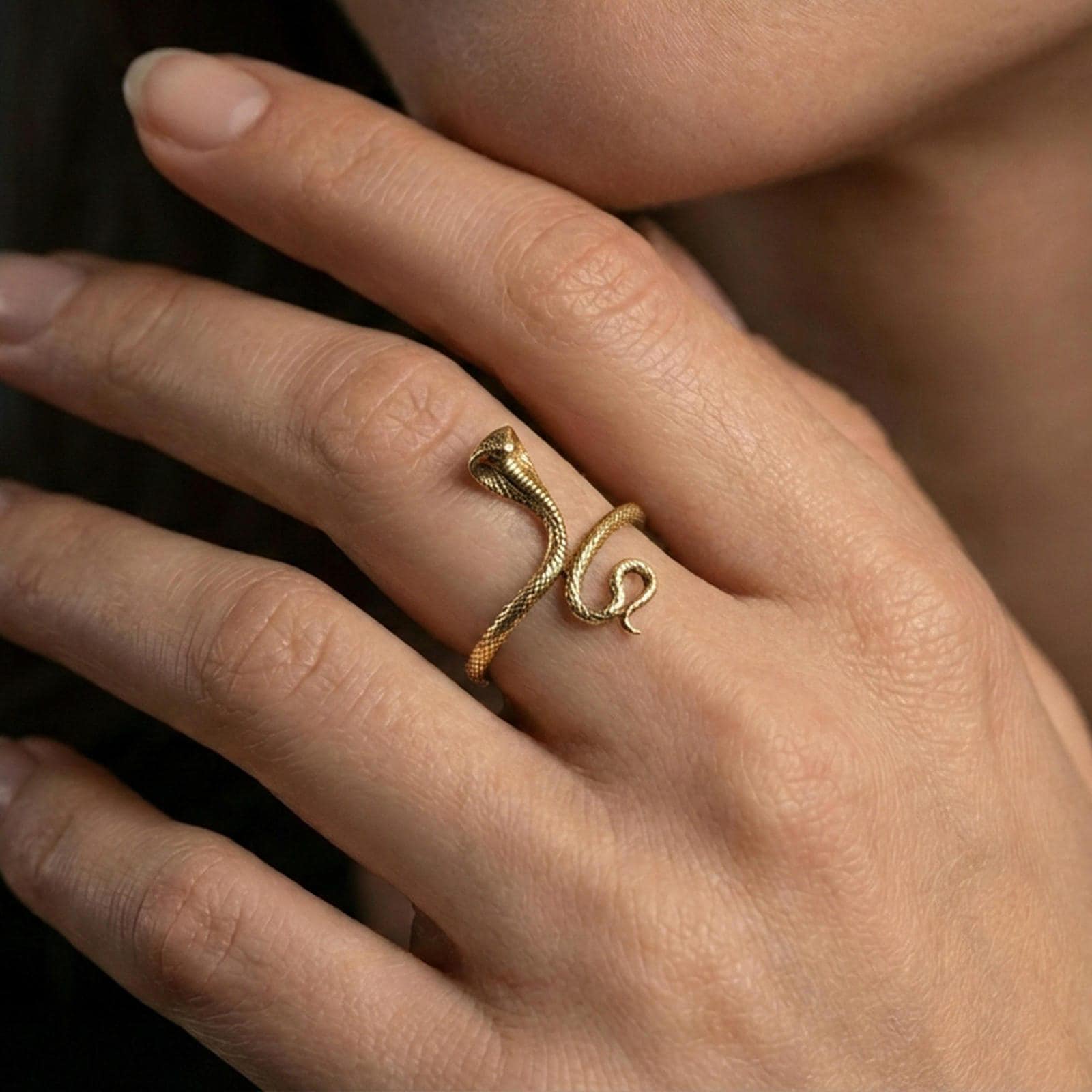 Gold plated cobra snake ring worn on finger, lifestyle wear shot emphasizing the bold upright cobra design and coiled tail detail