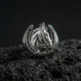 Load image into Gallery viewer, Polished silver horseshoe horse ring on volcanic rock surface, close-up highlighting the open horseshoe frame, detailed mane texture, and bridle engraving
