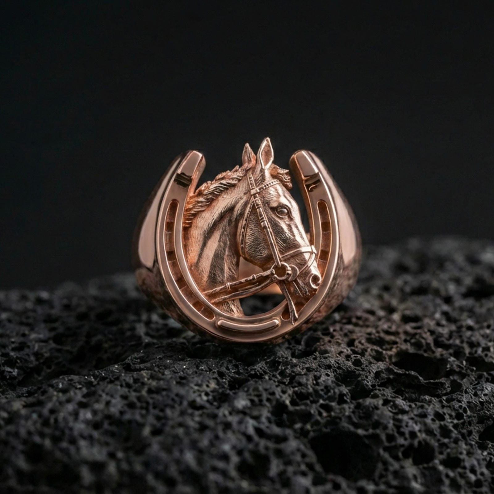 Rose gold plated horseshoe horse ring on volcanic rock, sharp macro product photo showcasing the horse head relief inside the horseshoe frame