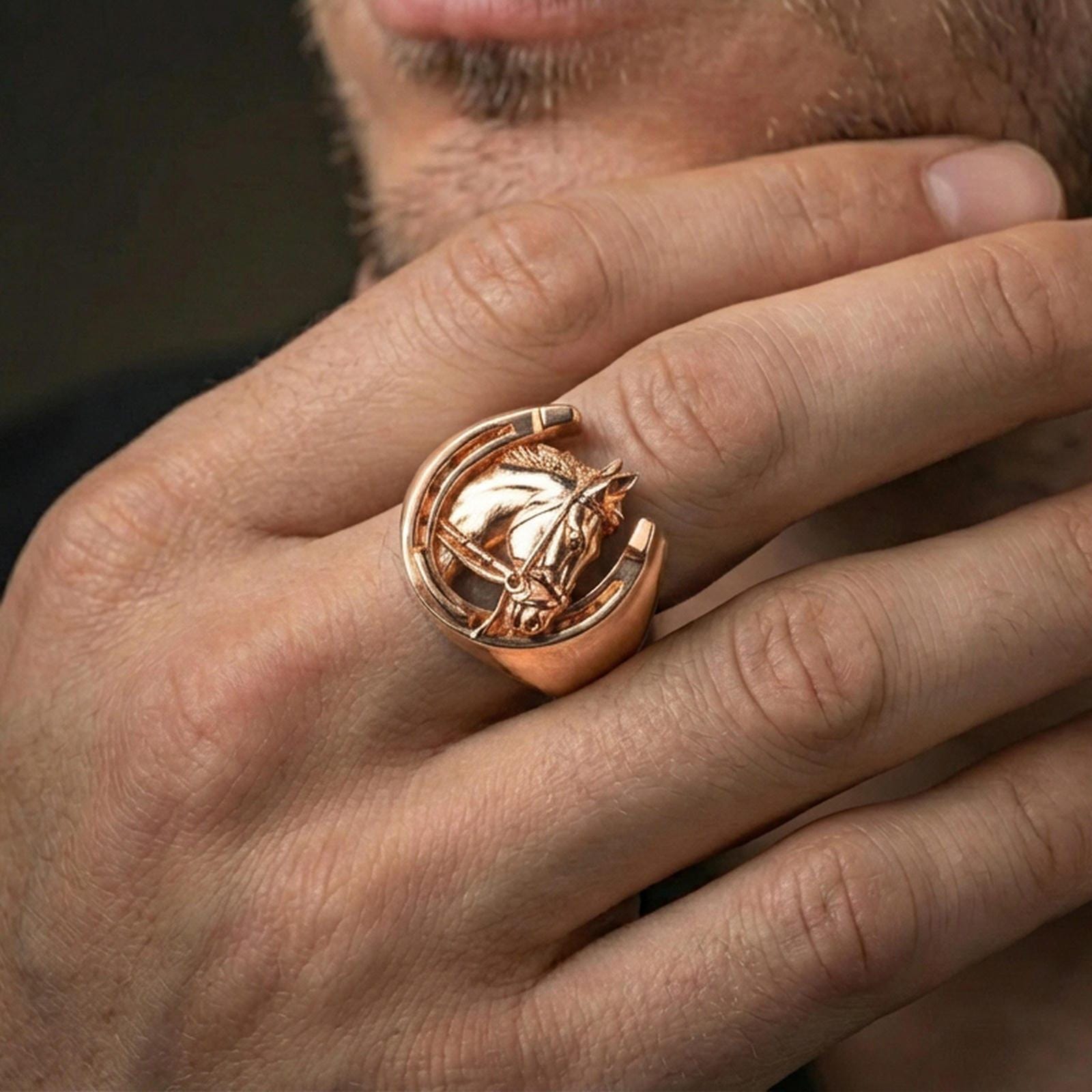 Rose gold plated horseshoe ring on finger, close-up lifestyle photo showcasing the horse head detail within the horseshoe frame and premium finish look