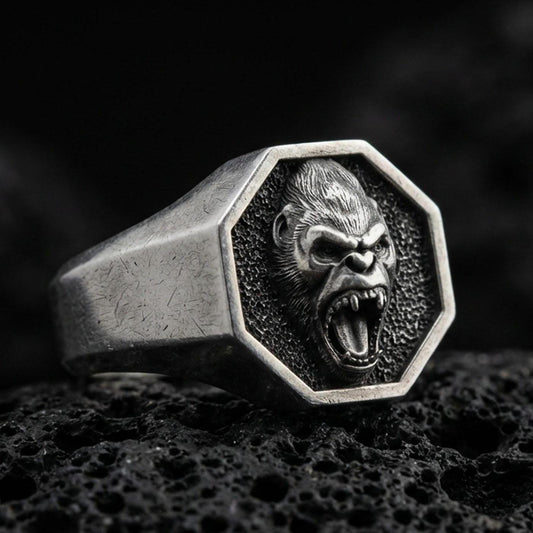 Close-up of an oxidized sterling silver octagon gorilla signet ring on porous volcanic rock in a dark studio shot
