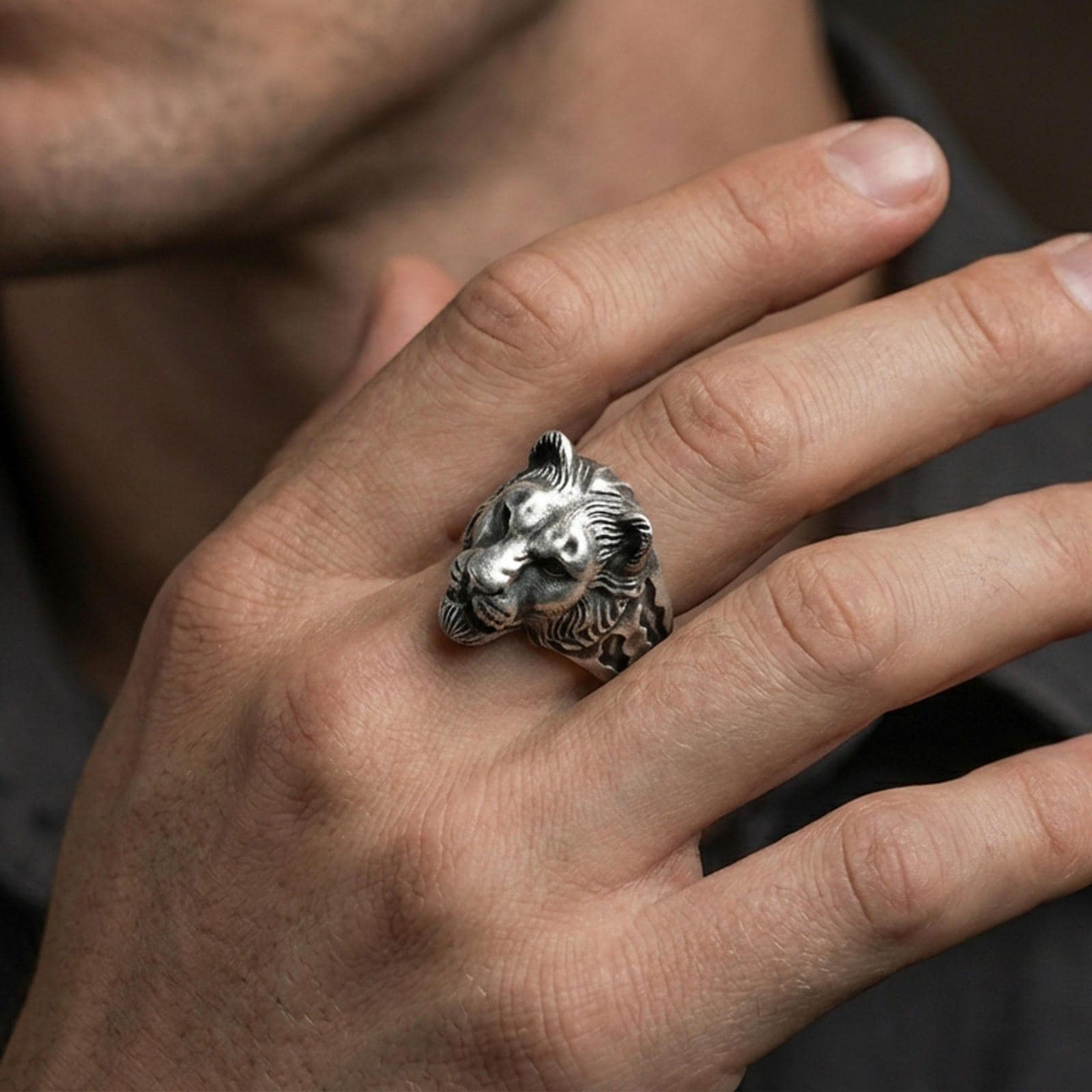 Oxidized sterling silver lioness ring worn on a finger, showing the bold animal head and side detailing