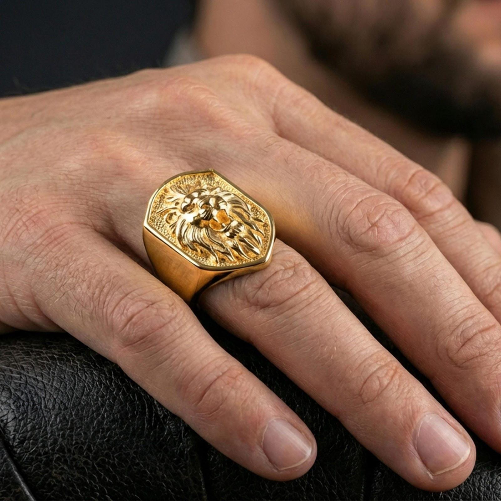 Gold plated lion ring worn on a finger with dark minimal background, emphasizing the roaring lion head relief