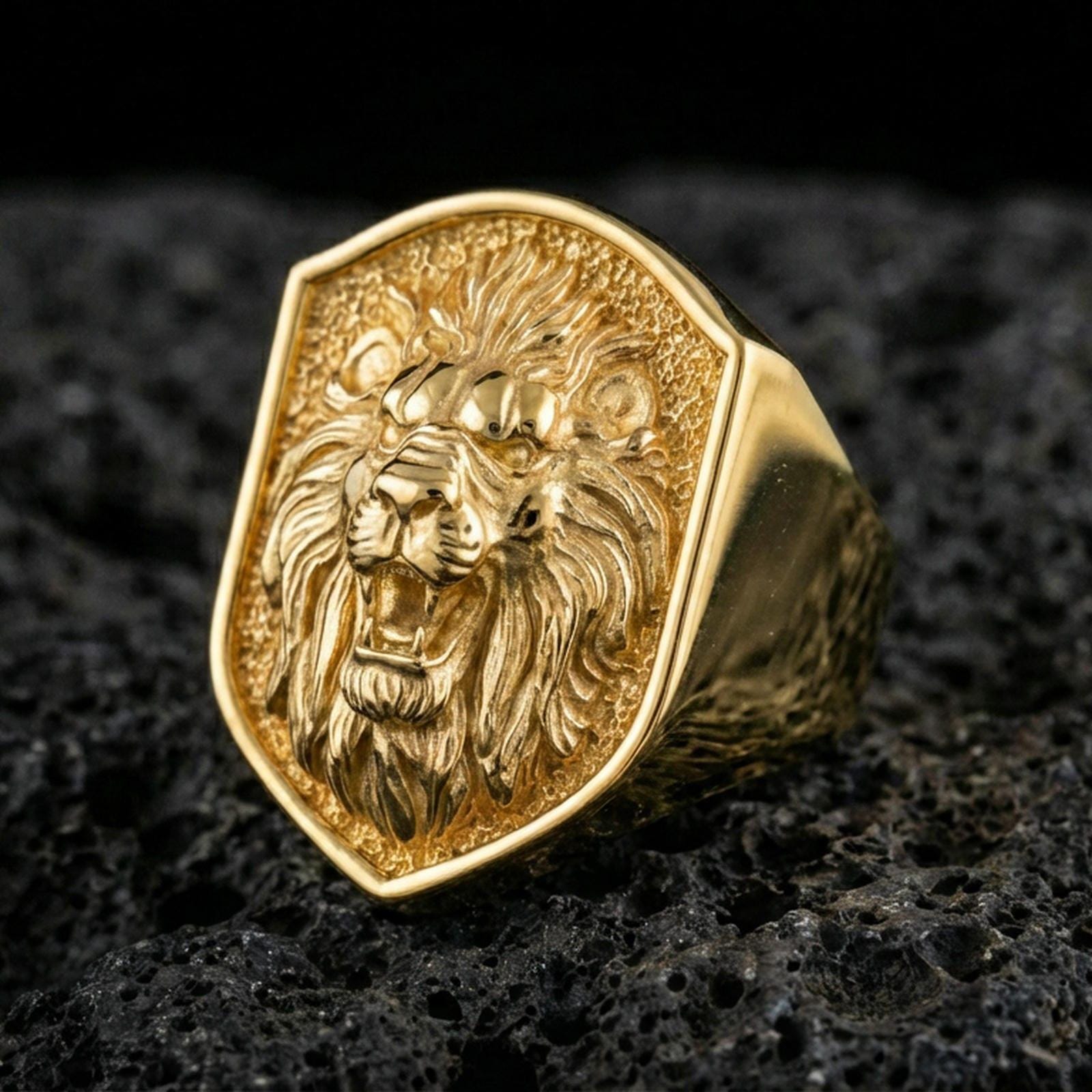 Gold plated roaring lion ring on black volcanic rock, macro focus on the sculpted mane and high-relief face