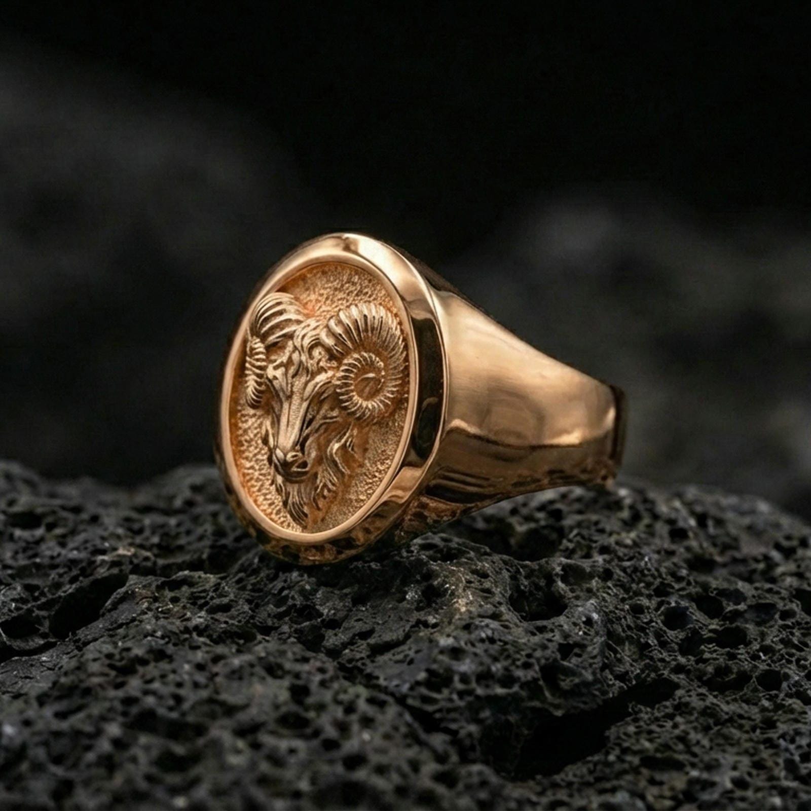 Rose gold plated ram head ring on porous volcanic rock with studio highlights and sharp relief definition