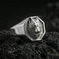 Load image into Gallery viewer, Polished silver geometric wolf ring on textured volcanic stone, macro focus on the wolf head relief and edges
