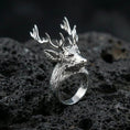 Load image into Gallery viewer, Polished silver deer antler ring on textured volcanic stone, macro focus on the carved fur and antlers
