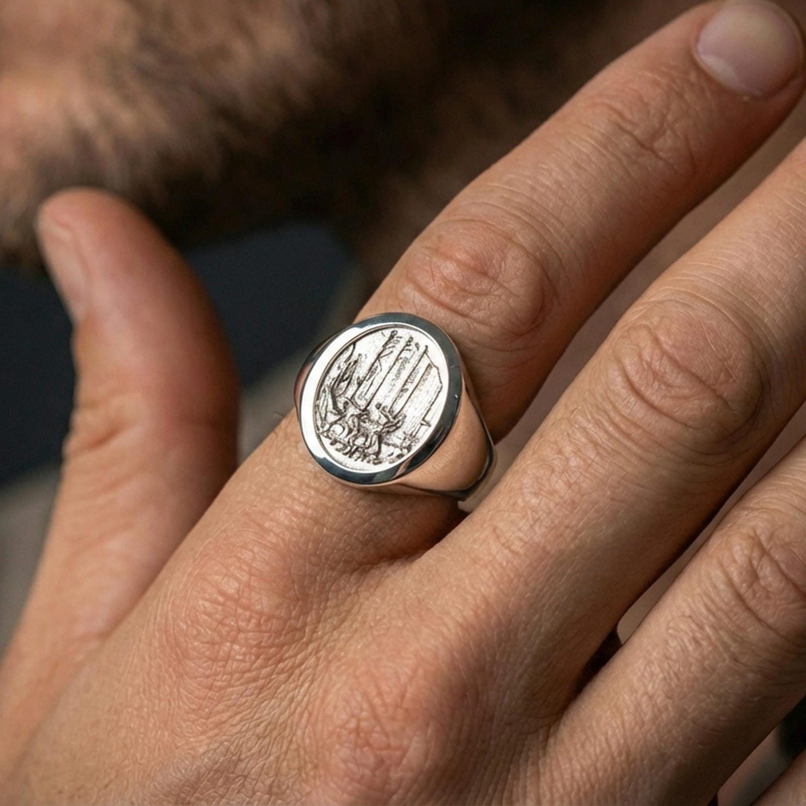 Polished silver woodland signet ring on a hand, macro view emphasizing the landscape engraving and ring profile
