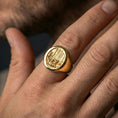 Load image into Gallery viewer, Gold plated nature signet ring worn on a finger, dark background with focus on the forest scene
