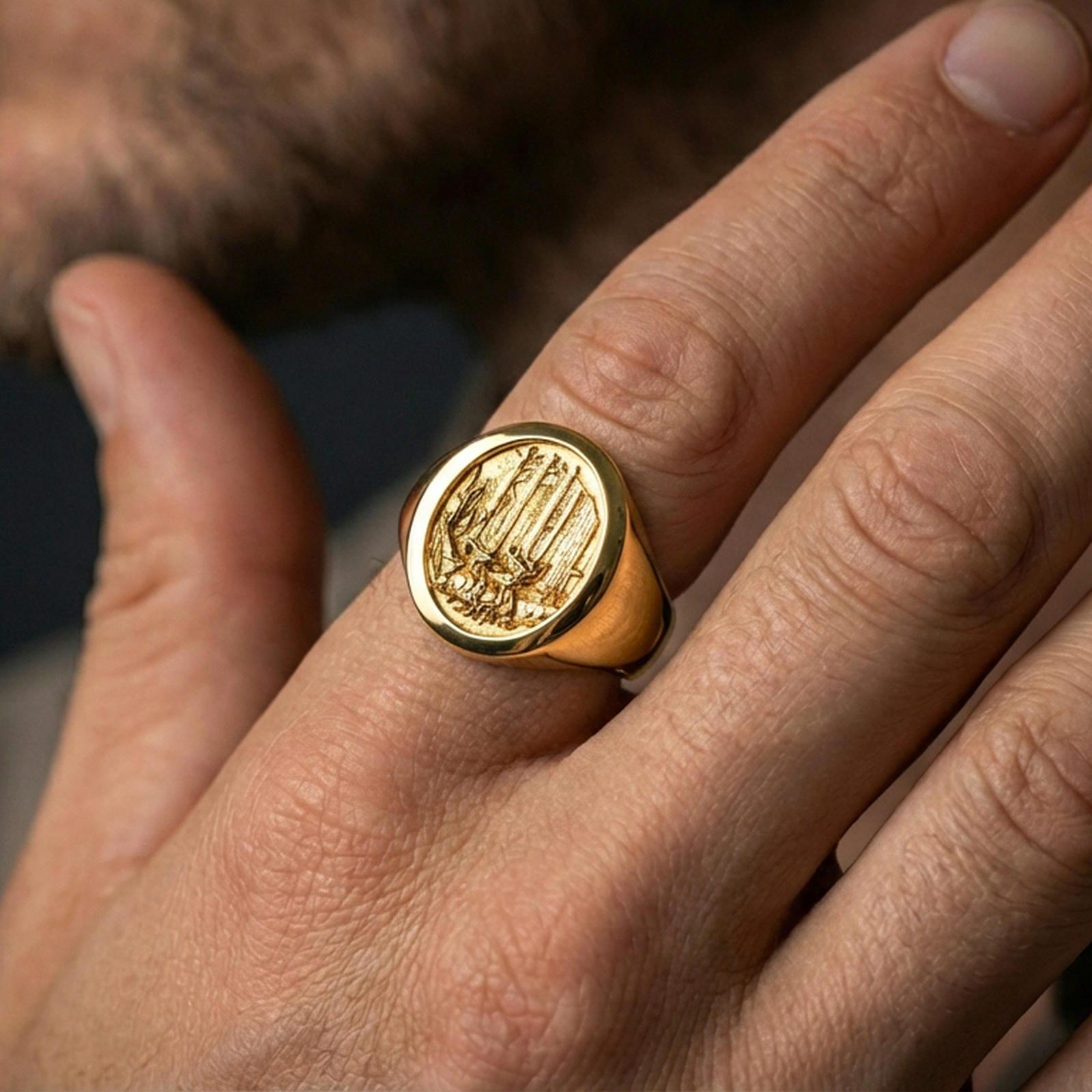 Gold plated nature signet ring worn on a finger, dark background with focus on the forest scene