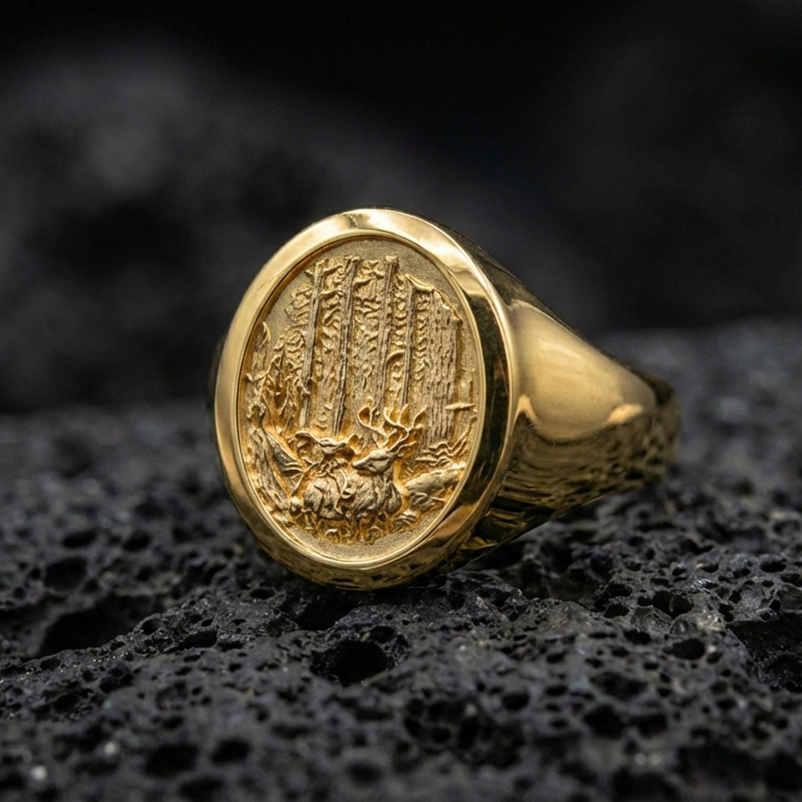 Gold plated forest scene signet ring on black volcanic rock with crisp highlights and deep shadows