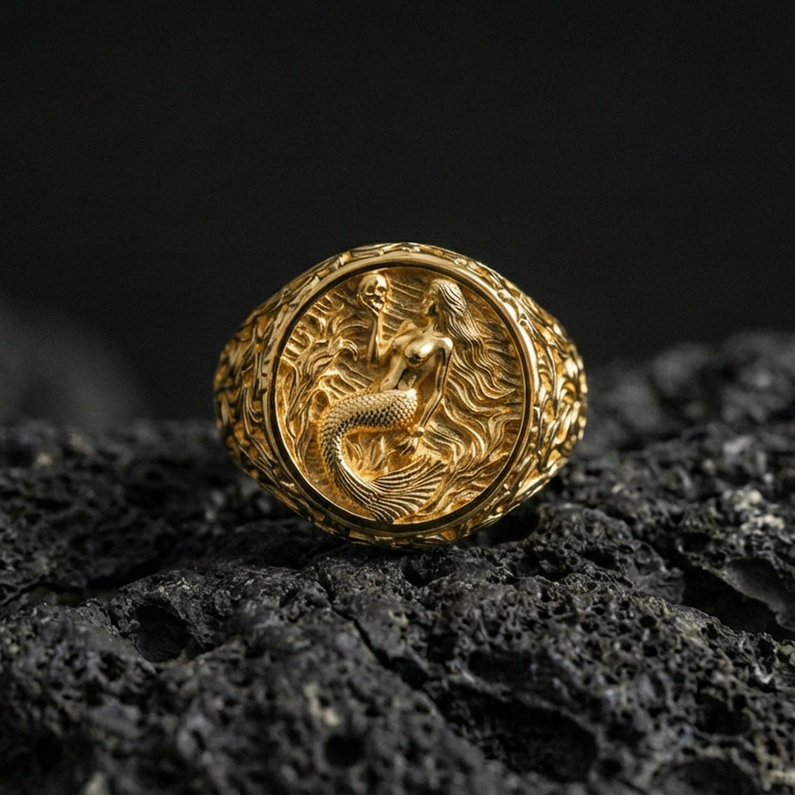 Gold plated mermaid ring displayed on porous volcanic rock, ocean-inspired fantasy relief with filigree band engraving, luxury macro shot