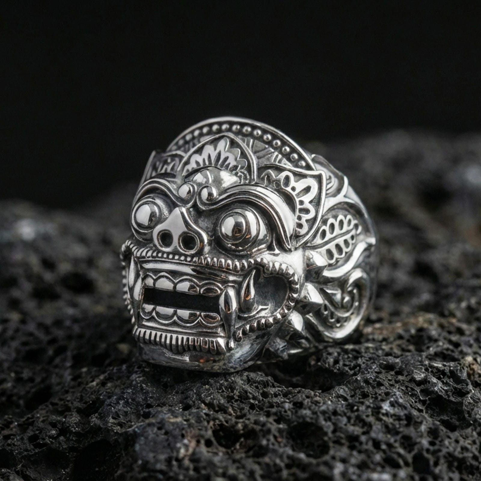 Balinese Barong god sterling silver ring in polished silver finish on volcanic rock, close-up carving detail