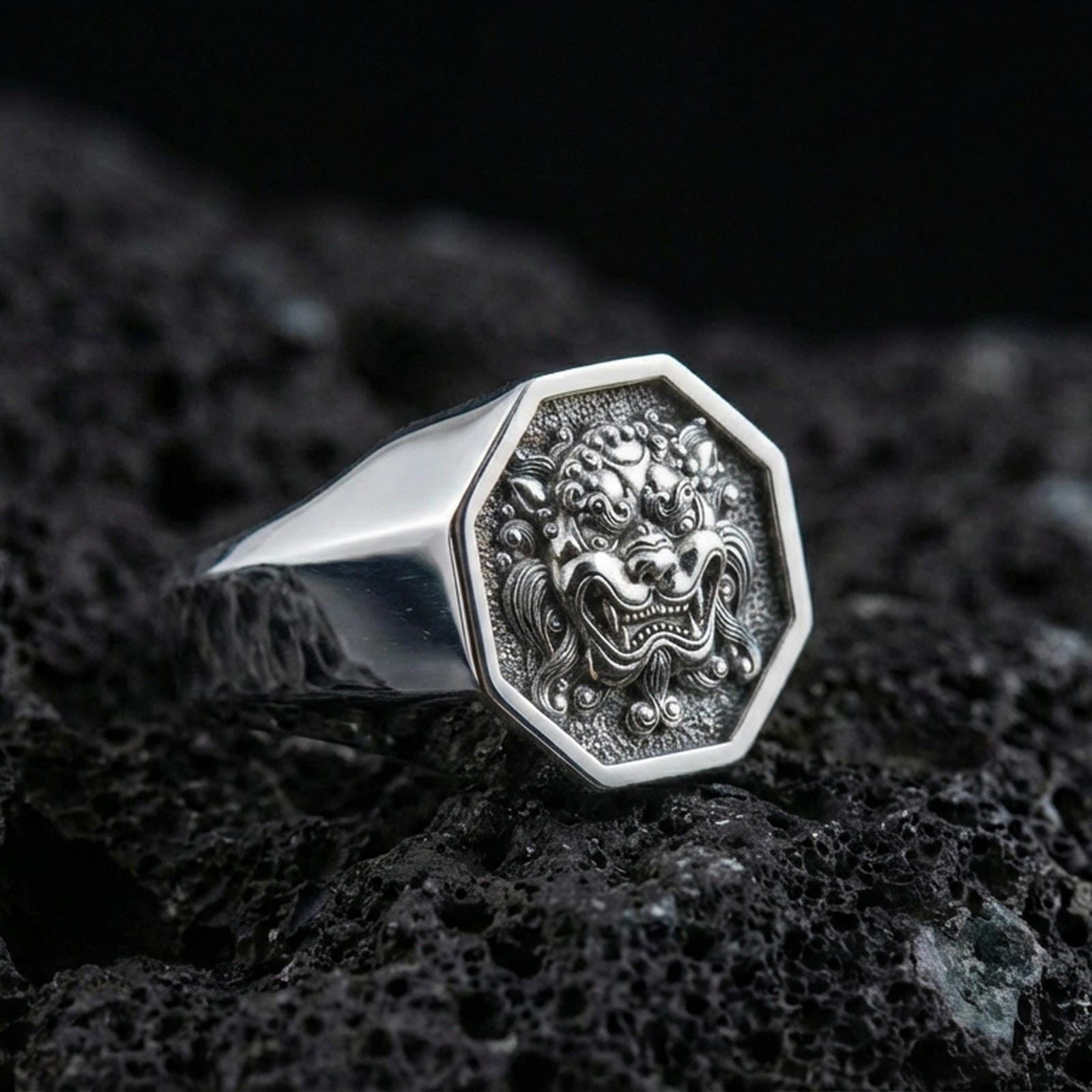 Octagon sterling silver Foo Dog signet ring in polished silver finish on volcanic rock, detailed guardian lion carving, close-up photo