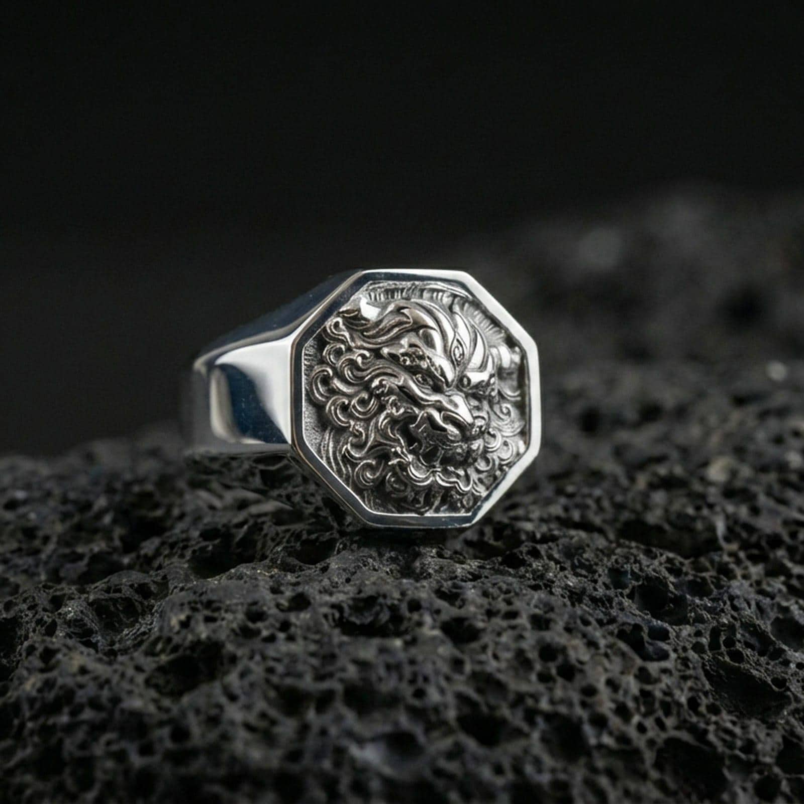 Octagon sterling silver Foo Dog signet ring in polished silver finish on volcanic rock, detailed guardian lion carving, close-up photo