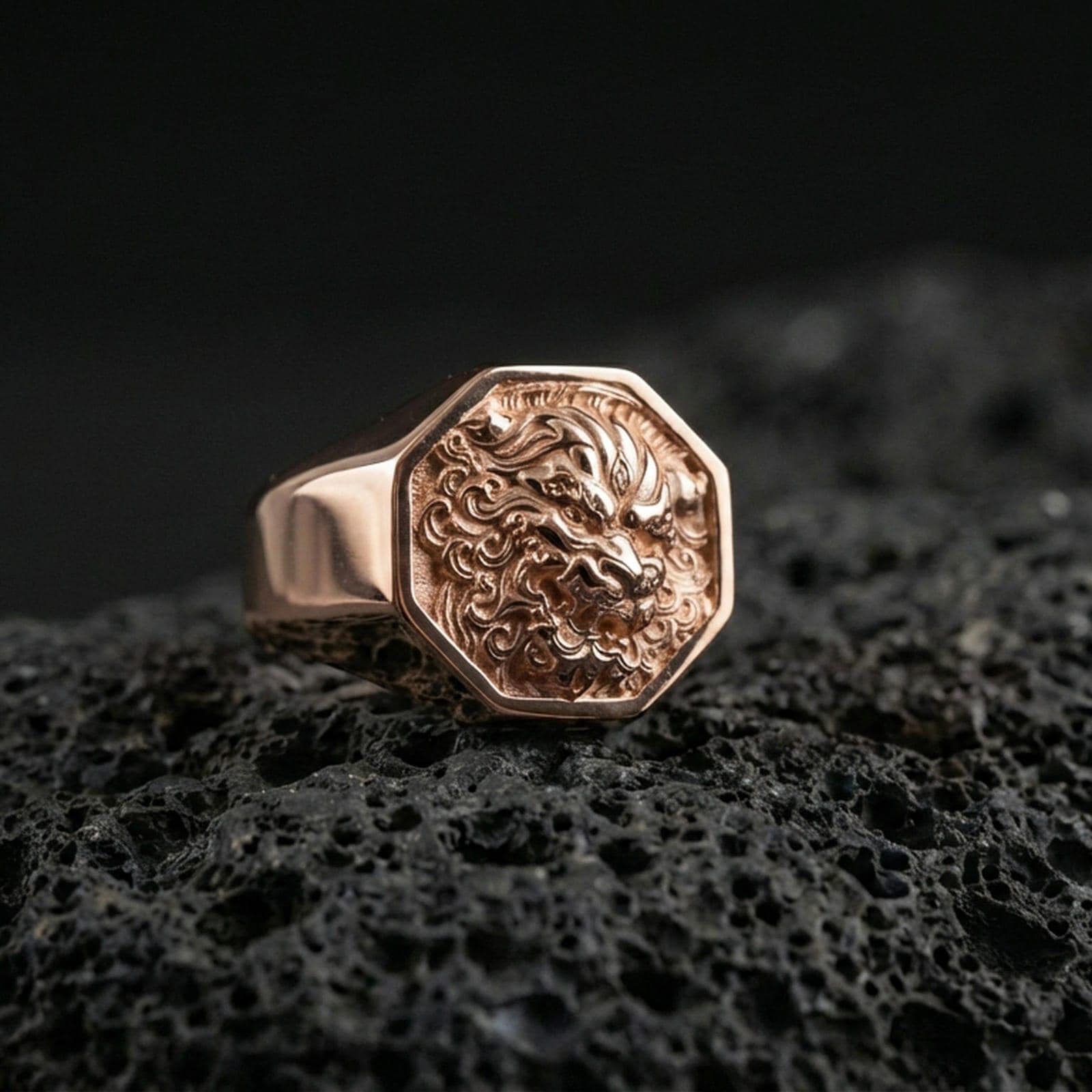Octagon Foo Dog signet ring in a rose gold plated finish on volcanic rock, ornate guardian lion relief detail, luxury studio close-up