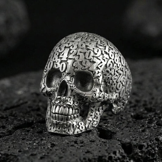925 sterling silver numerology skull signet ring in an oxidized finish on volcanic rock, Cronus-inspired memento mori design, macro studio shot